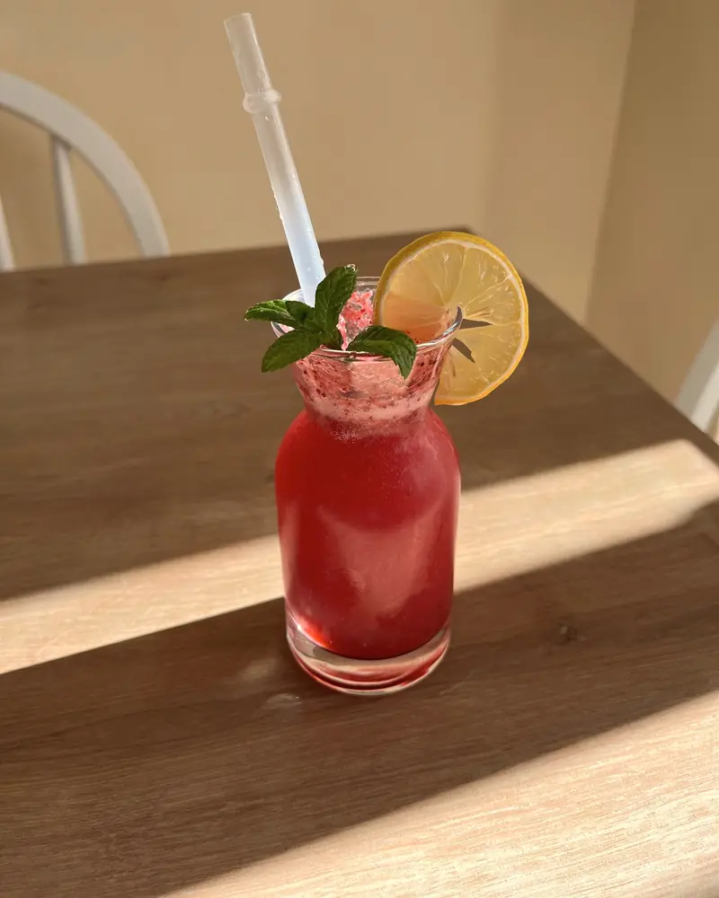 Malinová limonáda s mätou v pohári na drevenom stole